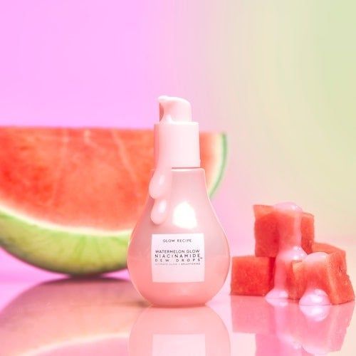 The Glow Recipe Watermelon Glow Niacinamide Dew Drops bottle placed in front of fresh watermelon slices and cubes