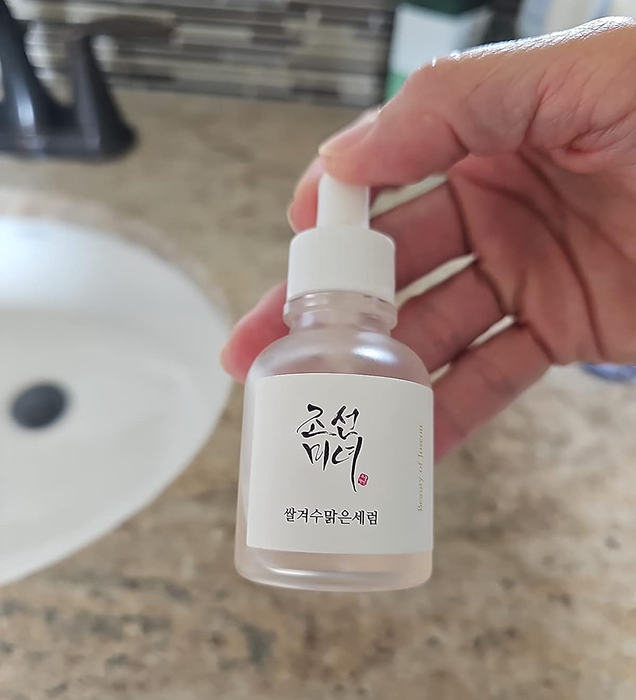 A reviewer holding the bottle of the serum