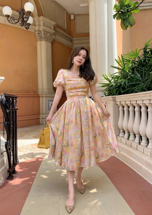 a model posing in a yellow and pink floral dress