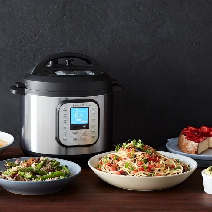 The Instant Pot placed in front of a pasta entrée with a side dish.