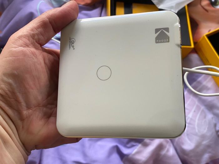 A reviewer showing the projector in their hands