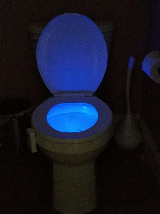 A reviewer's photo of the same light installed on the toilet, now emitting a blue light into the bowl.
