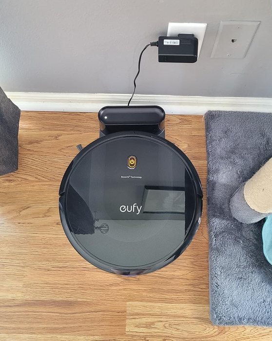 A reviewer photo showing the vacuum resting on its charging dock, plugged in and ready to go.