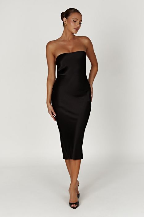 A model striking a pose in the black midi dress.