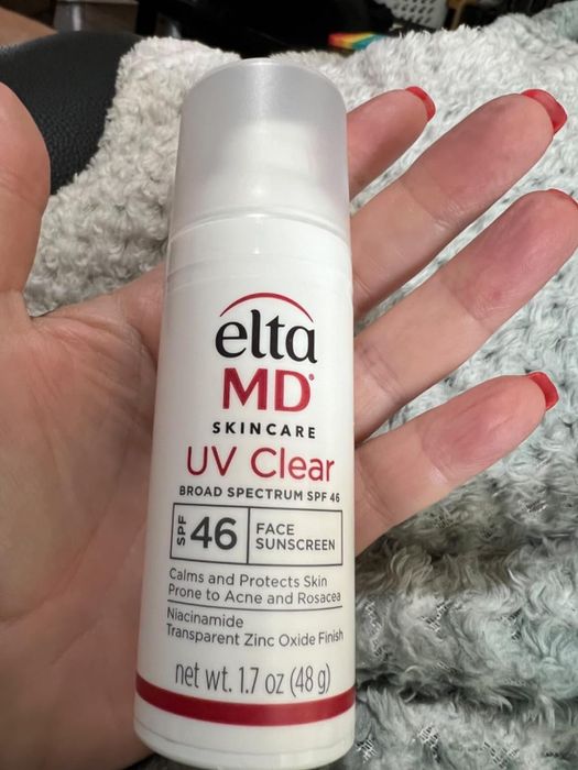 A hand holding a bottle of EltaMD Skincare UV Clear Broad-Spectrum SPF 46 sunscreen