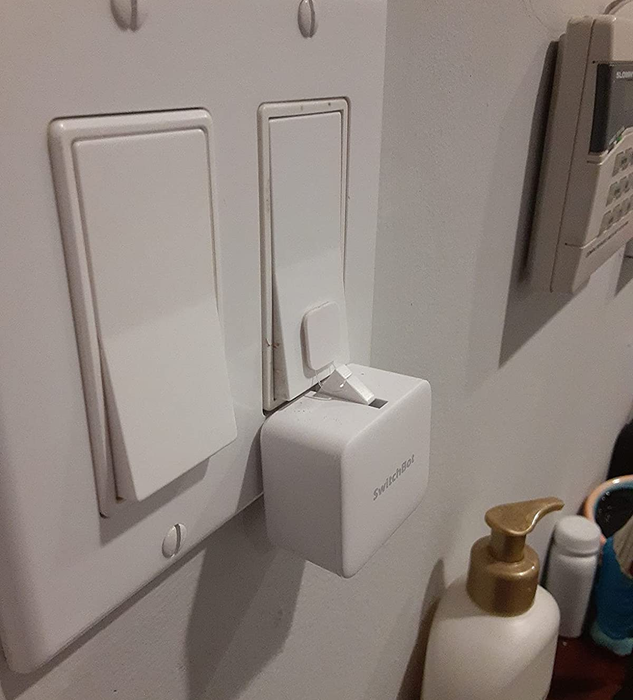 A reviewer photo showing the white SwitchBot mounted on a light switch.