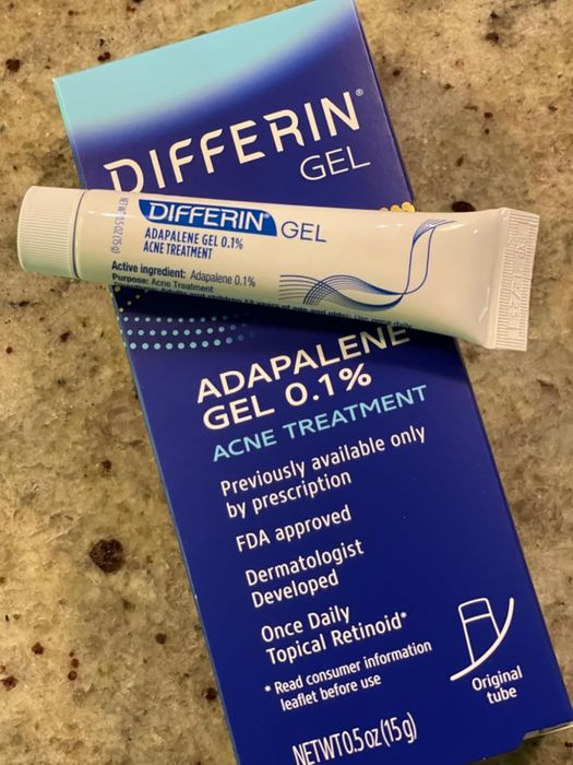 The packaging of Differin Gel (adapalene 0.1%) acne treatment shows the box and tube with emphasis on FDA approval and its dermatologically developed formula, highlighting its recommended once-daily use.