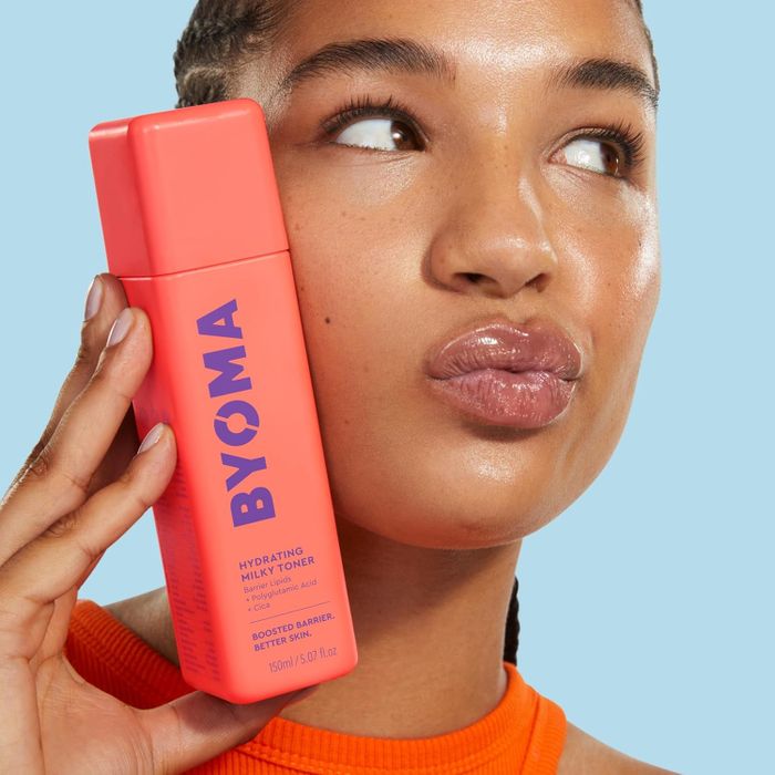 A person is seen holding a bottle of BYOMA Hydrating Milky Toner near their face, looking pensive and contemplative.