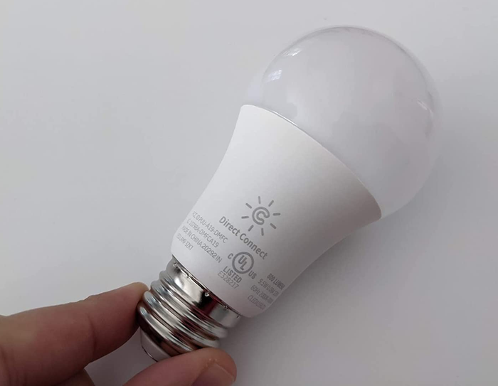 A reviewer holding one of the smart light bulbs in their hand.