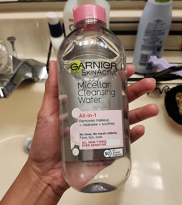 The reviewer holding the bottle of micellar water
