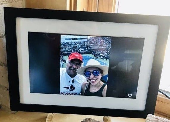 The frame featuring a black-and-white border around a digital display, showcasing a picture of the reviewer and their father at a tennis match.