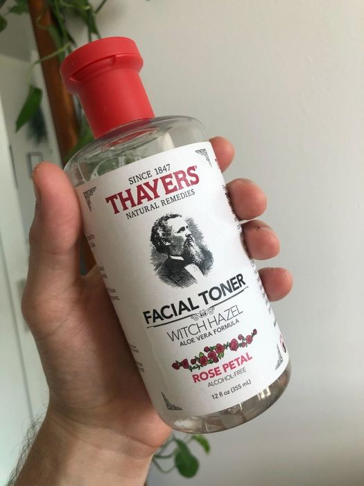 A reviewer holding the red and white bottle, which notes that the toner has been in production since 1847.