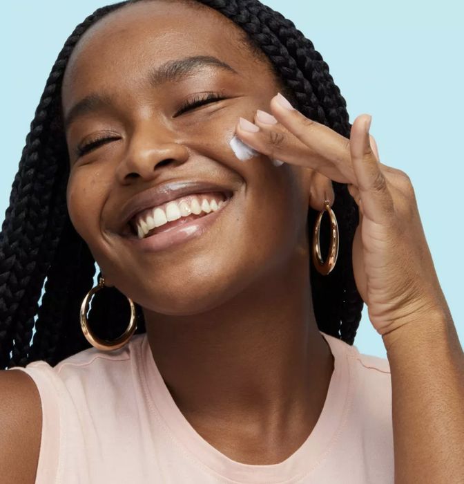 A person applying the moisturizer onto their skin.
