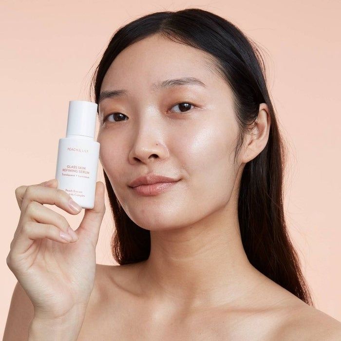 A person holding the serum next to their face, showcasing its glow-enhancing properties.