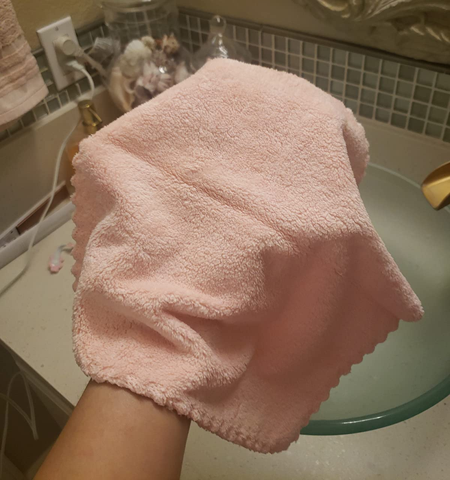 The reviewer is holding their pink makeup-removing cloth in hand.