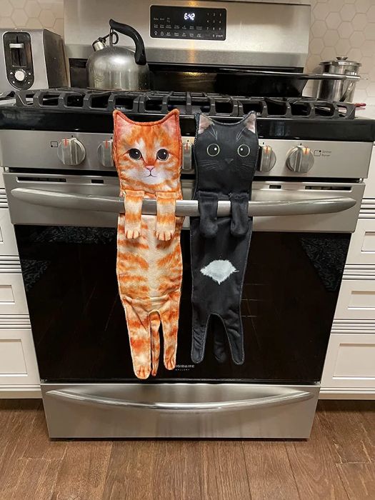 An orange cat towel and a black cat towel hanging from a reviewer's oven door