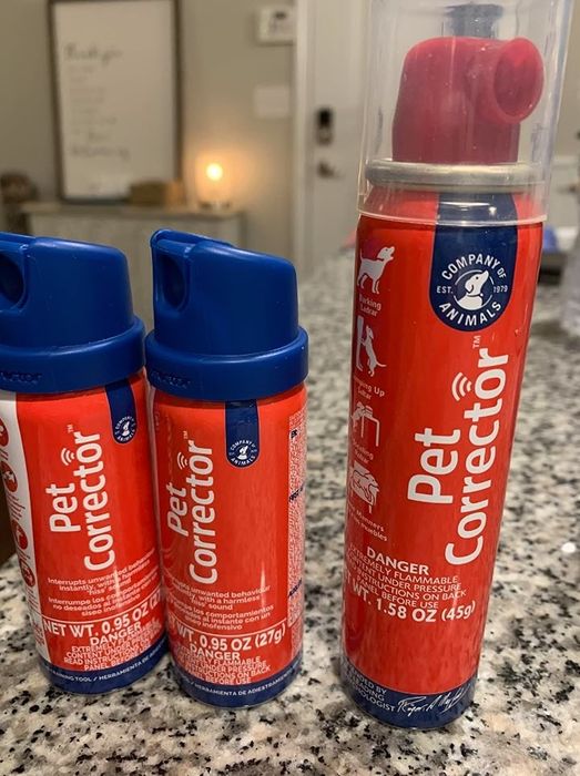 Three cans of Pet Corrector spray arranged on a countertop.