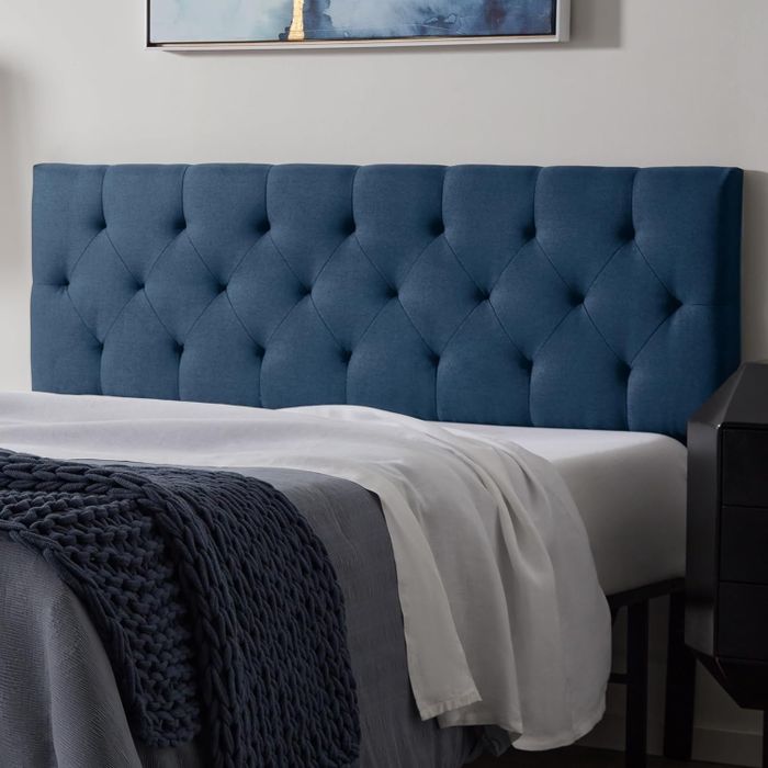 Tufted navy headboard with a diamond pattern in a stylish bedroom arrangement.