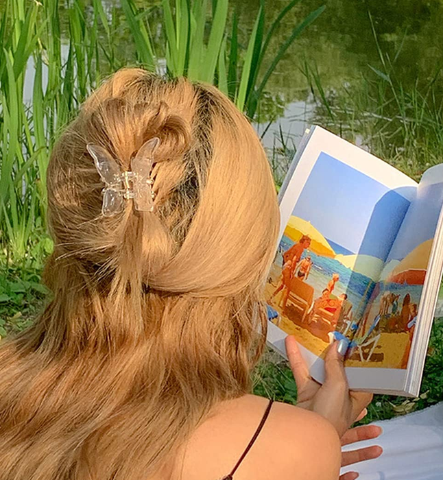 The model has a clear butterfly clip in their hair.