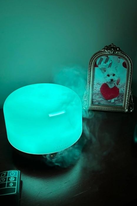 A diffuser glowing with teal light on a nightstand.