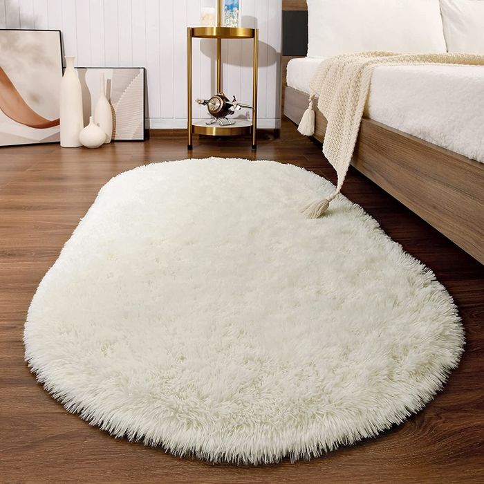 The white rug placed next to a bed.