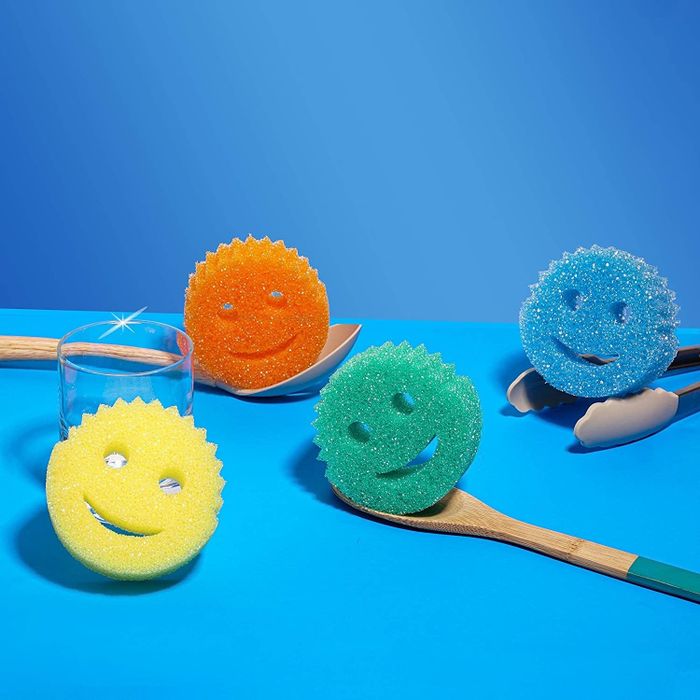 Four 1-inch thick, round sponges with smiley faces, each featuring two eye holes and a crescent-shaped mouth hole.