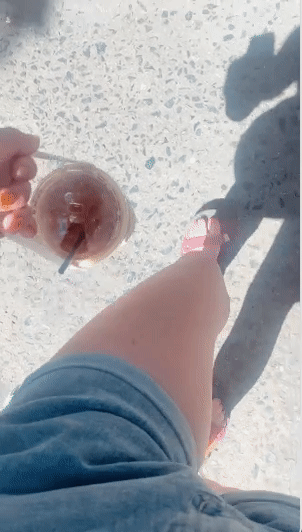 An editor using the cup holder with the long handle to walk down the street while holding iced coffee.