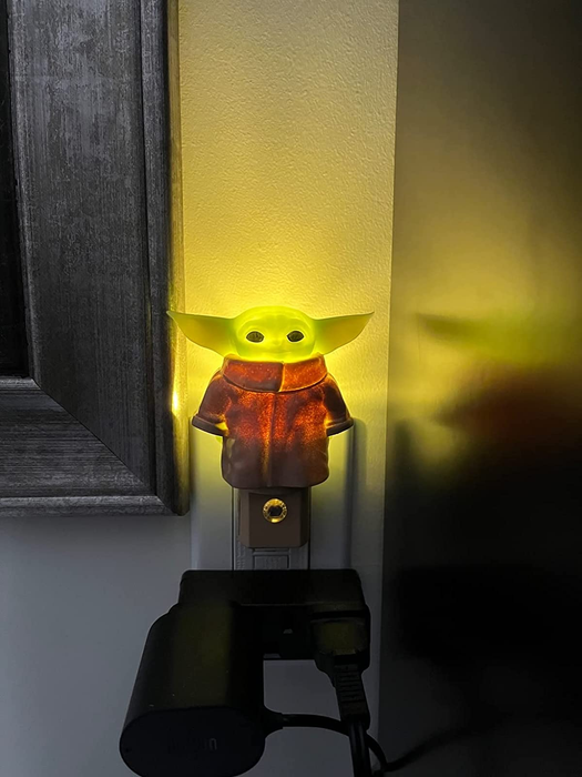 A reviewer shows their Baby Yoda nightlight glowing in the dark.