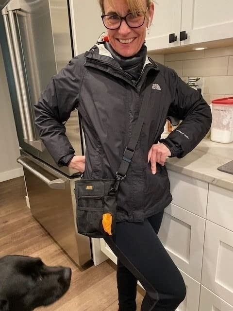 A reviewer is pictured wearing the treat pouch like a crossbody bag.