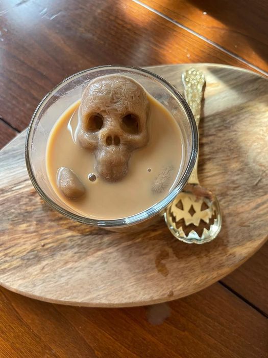 A skull-shaped ice cube floating in a cup of coffee.