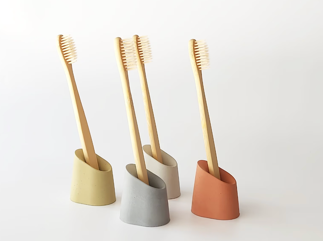 Concrete toothbrush holders in shades of yellow, beige, blue, and red.