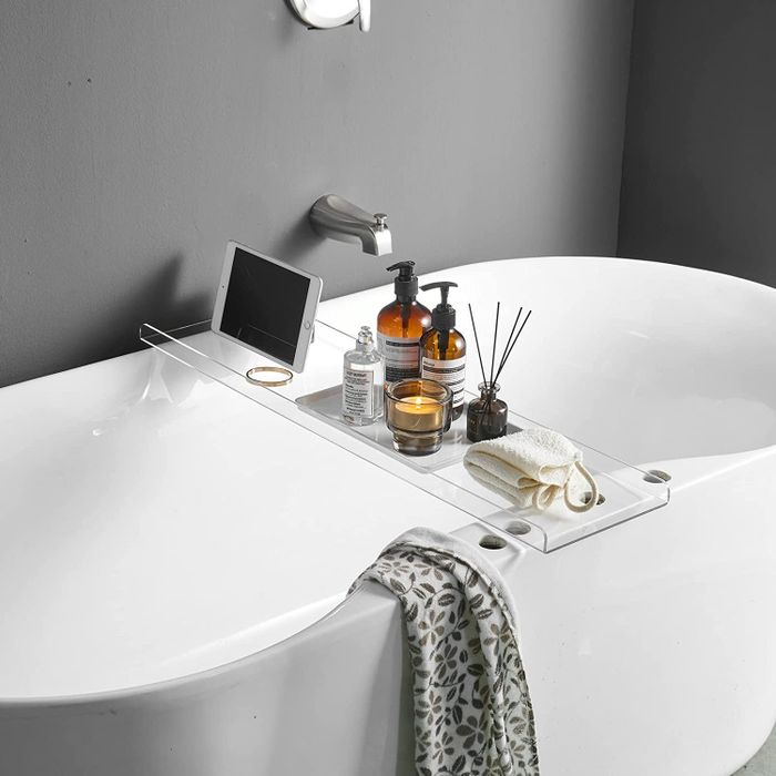 Acrylic bathtub caddy holding an iPad, perfume, soap, candle, and diffuser