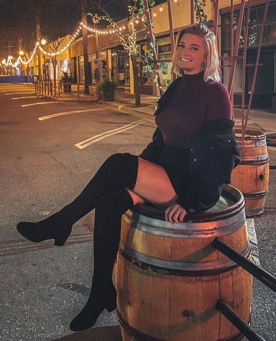 A reviewer is shown wearing boots paired with a skirt.