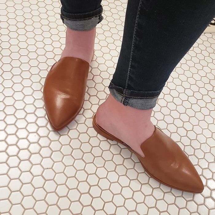 A reviewer wearing brown backless flats.
