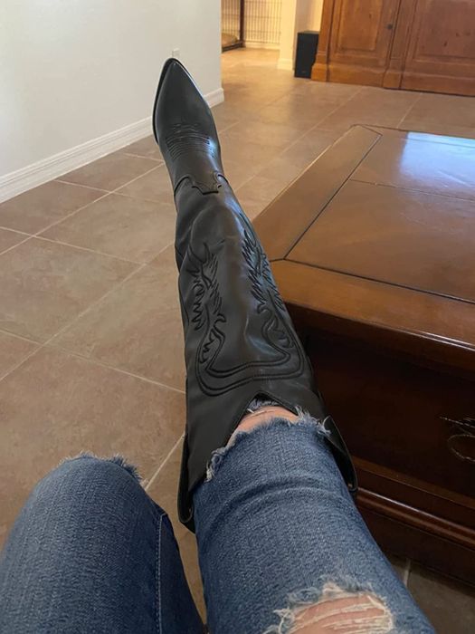 Another reviewer showcasing the embroidery details of the black faux leather boots over a pair of jeans.