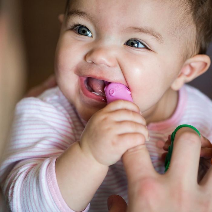 A child happily chewing on the silicone toothbrush.