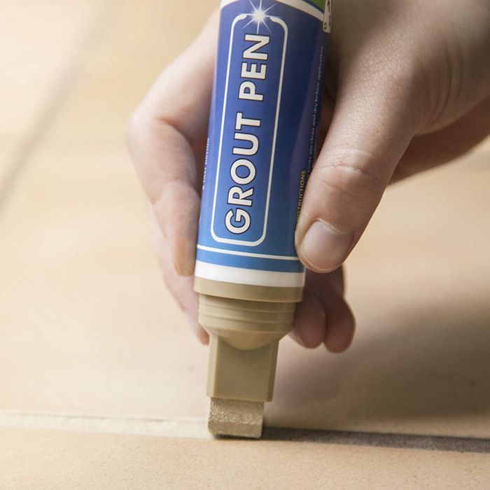 Someone using the grout pen, which features a precision tip for accuracy.