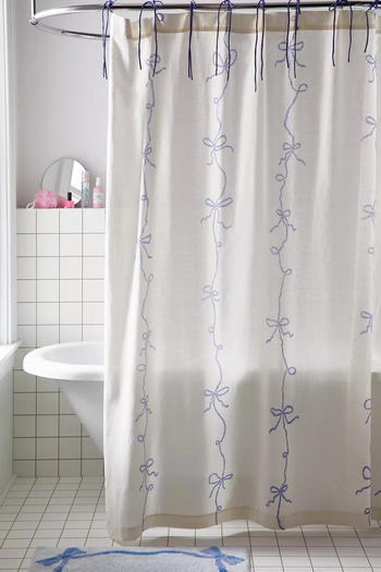 A white shower curtain featuring a blue bow design.