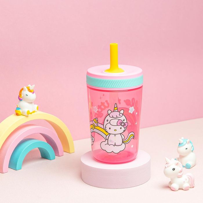 A children's sippy cup featuring a whimsical unicorn design, accompanied by a small toy rainbow and unicorn figurines for added charm.