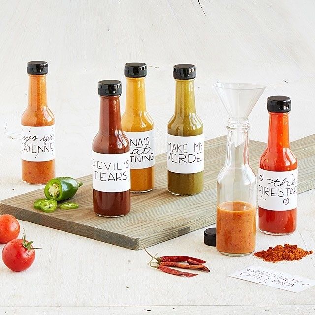 Six bottles of hot sauce, each labeled and made from the DIY kit.