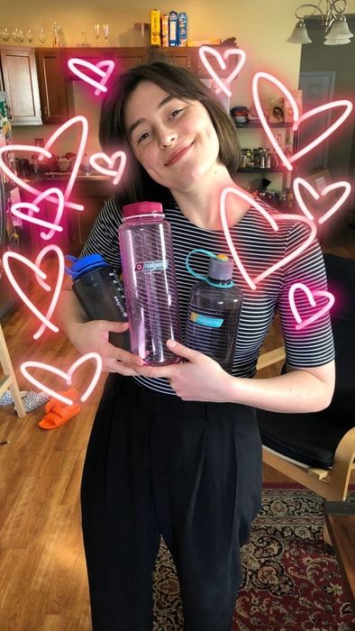 The writer holding three Nalgenes with hearts drawn around them