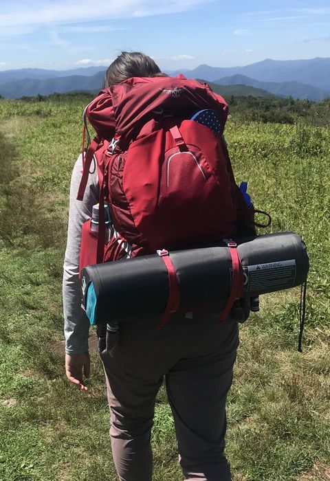 The writer is seen walking along the trail with the Osprey pack, a sleeping mat securely attached to the outside, showing how versatile and practical the pack can be for extended trips.