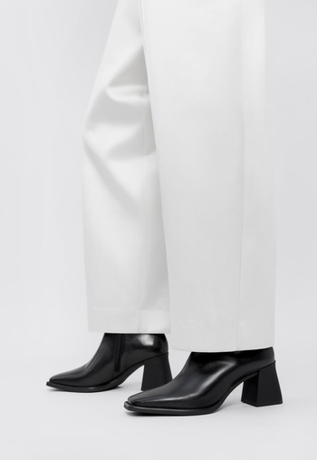 Close-up shot of a person wearing wide-legged pants and black leather ankle boots with square heels.