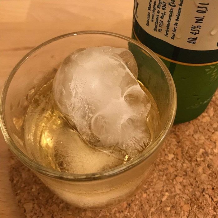 A skull-shaped ice cube chilling in a whiskey glass.