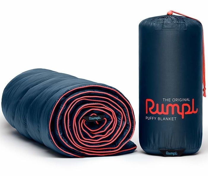 A blanket neatly rolled up, resting beside its convenient carrying bag, ready to be packed away for the next adventure.