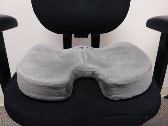 A reviewer's swivel office chair with a memory foam cushion placed on it.