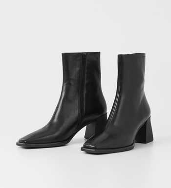 A pair of sleek black leather ankle boots featuring square toes and chunky heels, set against a minimalist background.