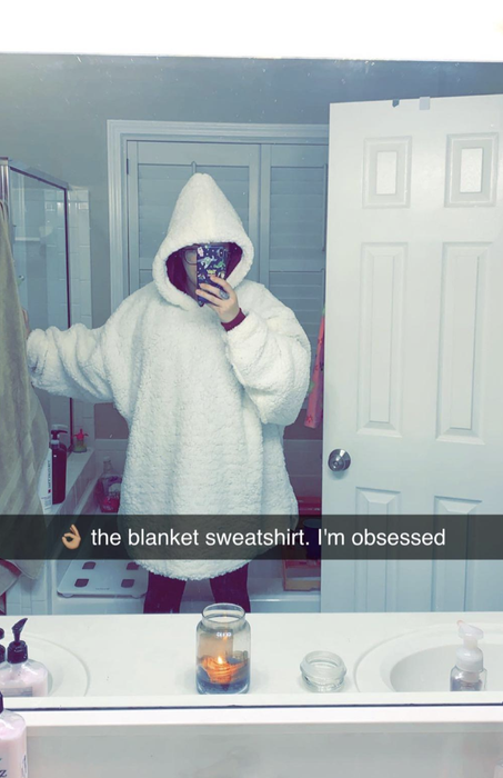 A reviewer wearing an oversized white blanket hoodie.