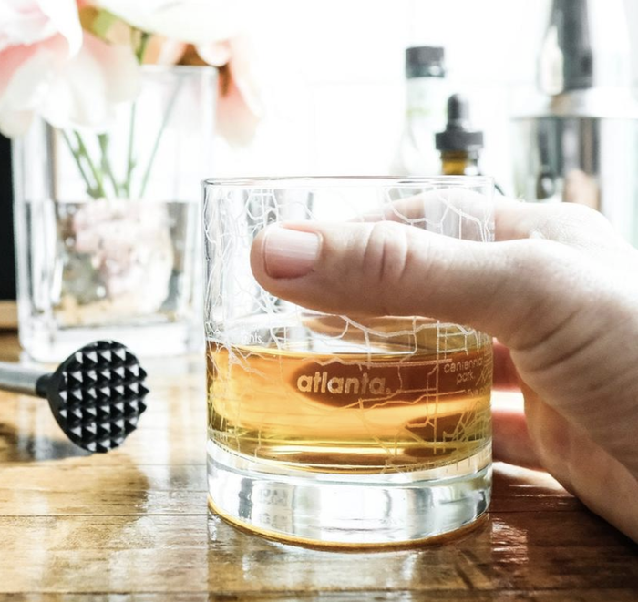 A clear whiskey glass with a detailed map of Atlanta etched into the glass.