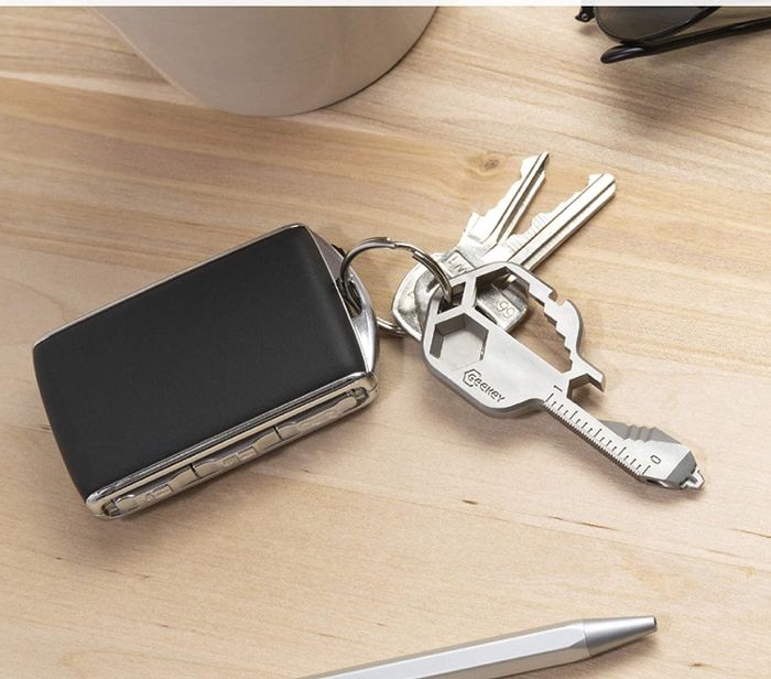 A small steel tool shaped like a key, featuring various grooves and measurements.